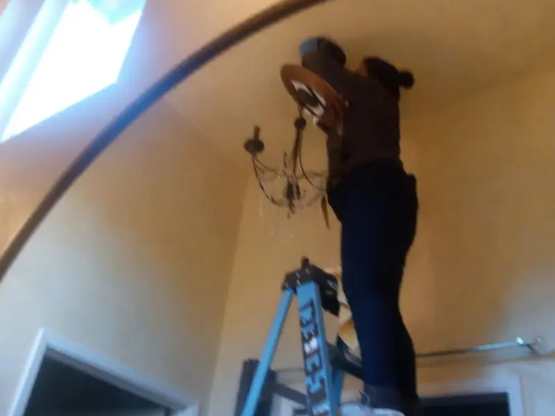 Electrician installing a chandelier in a Olivarez residence